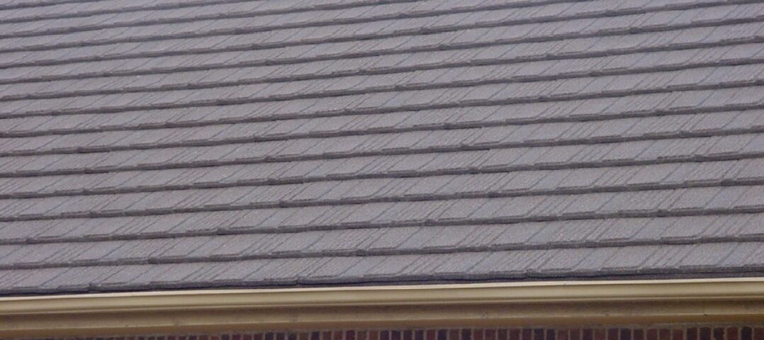 Gray shingle roof on a brick house with a gutter along the edge in Santa Clara